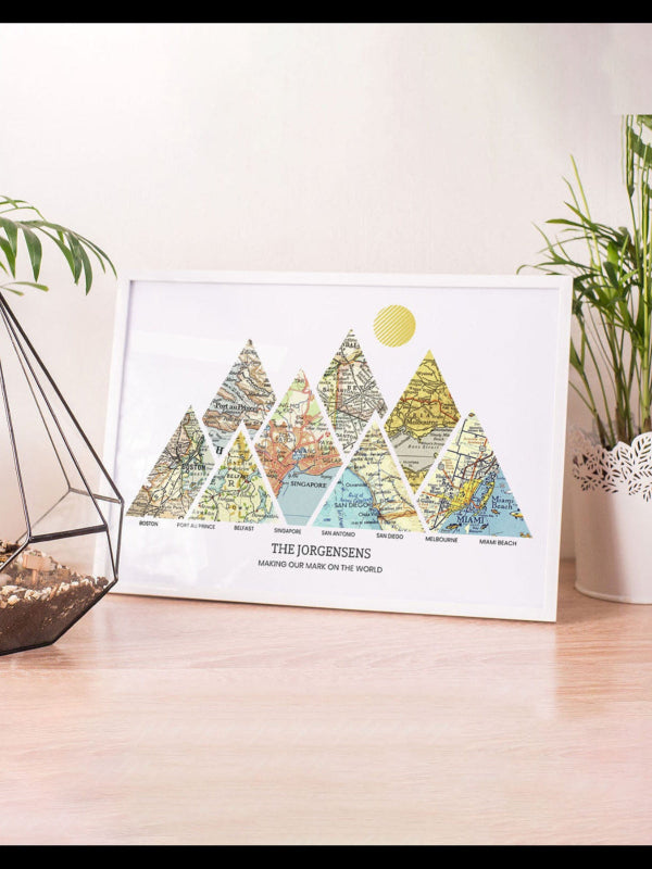 Framed map art of mountains on a wooden surface with plants in the background