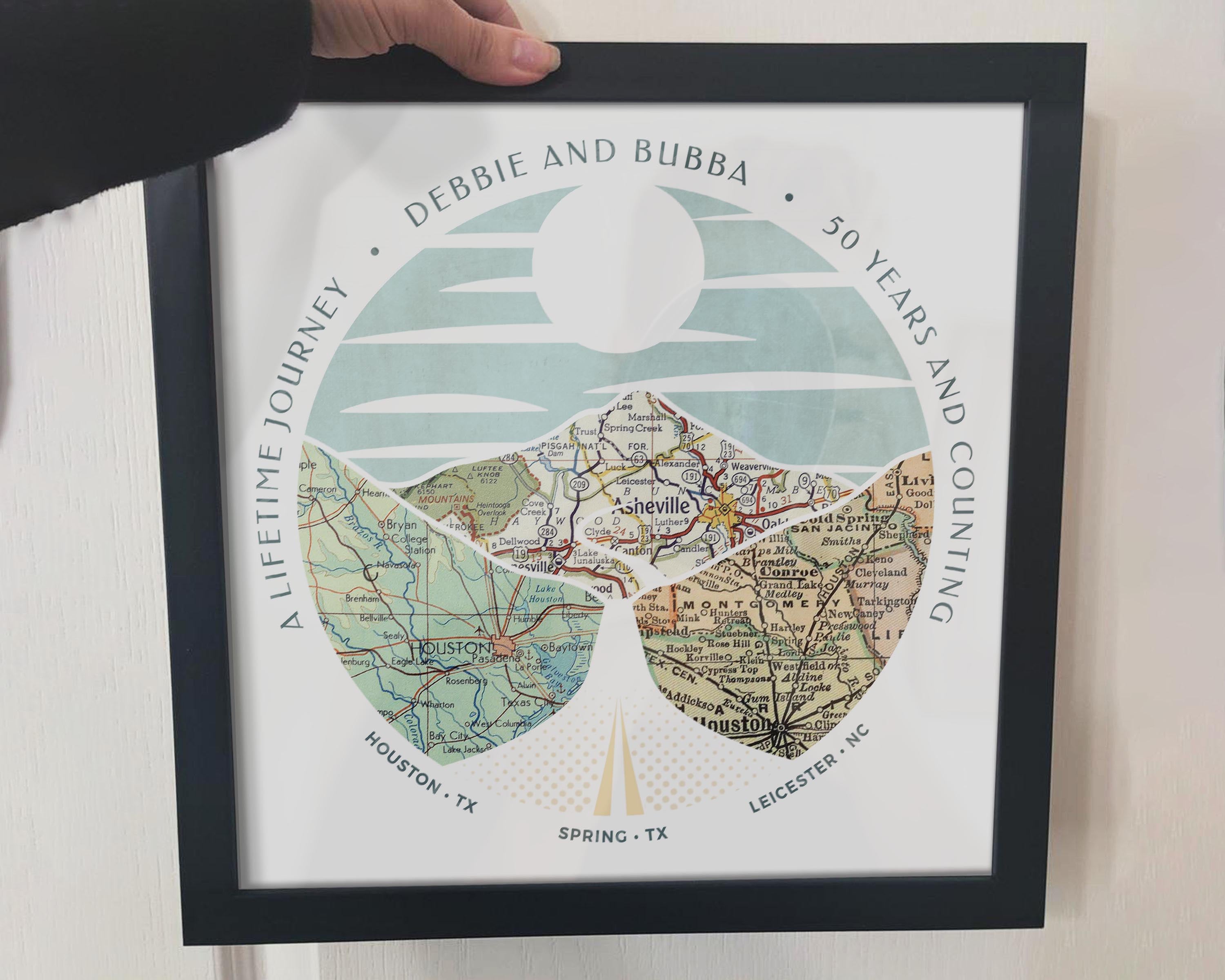 [Black Frame|12x12|3 Maps] Relief of hills and highway into the horizon, with inset maps. Hand holding frame.