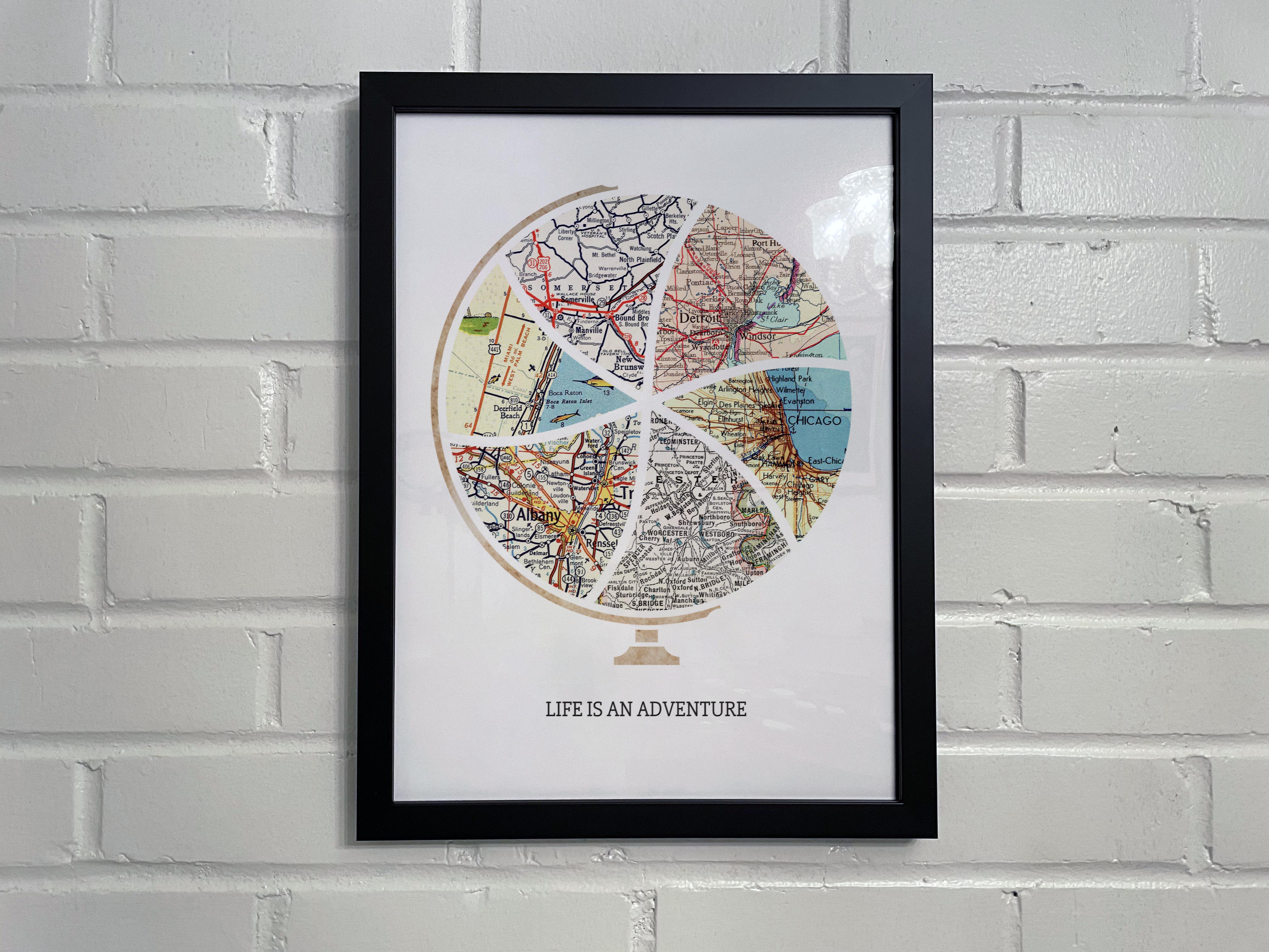 [Black Frame|12x16|6 Maps] Globe and stand relief design with inset maps. On white brick wall.
