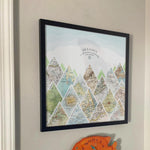 [Black Frame|18x18|16 Maps] Mountain scape relief with inset maps and geometric clouds above. Hanging in customer's home.