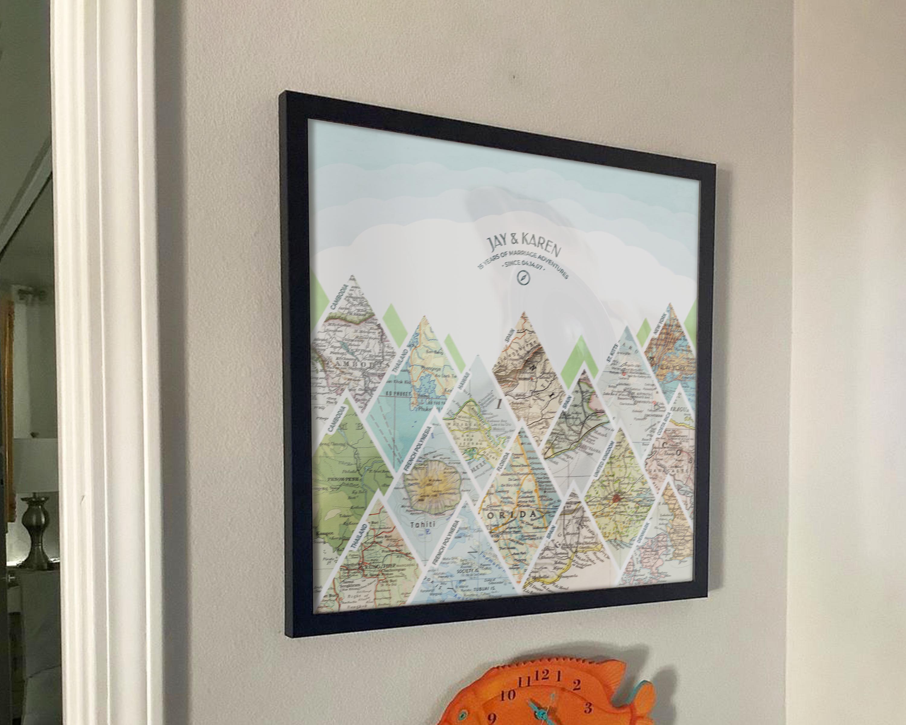 [Black Frame|18x18|16 Maps] Mountain scape relief with inset maps and geometric clouds above. Hanging in customer's home.