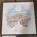 [Walnut Canvas|24x24|3 Maps] Relief of hills and highway into the horizon, with inset maps. Sitting flat on a table.