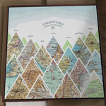 [Walnut Canvas|24x24|15 Maps] Mountain scape relief with inset maps and geometric clouds above.