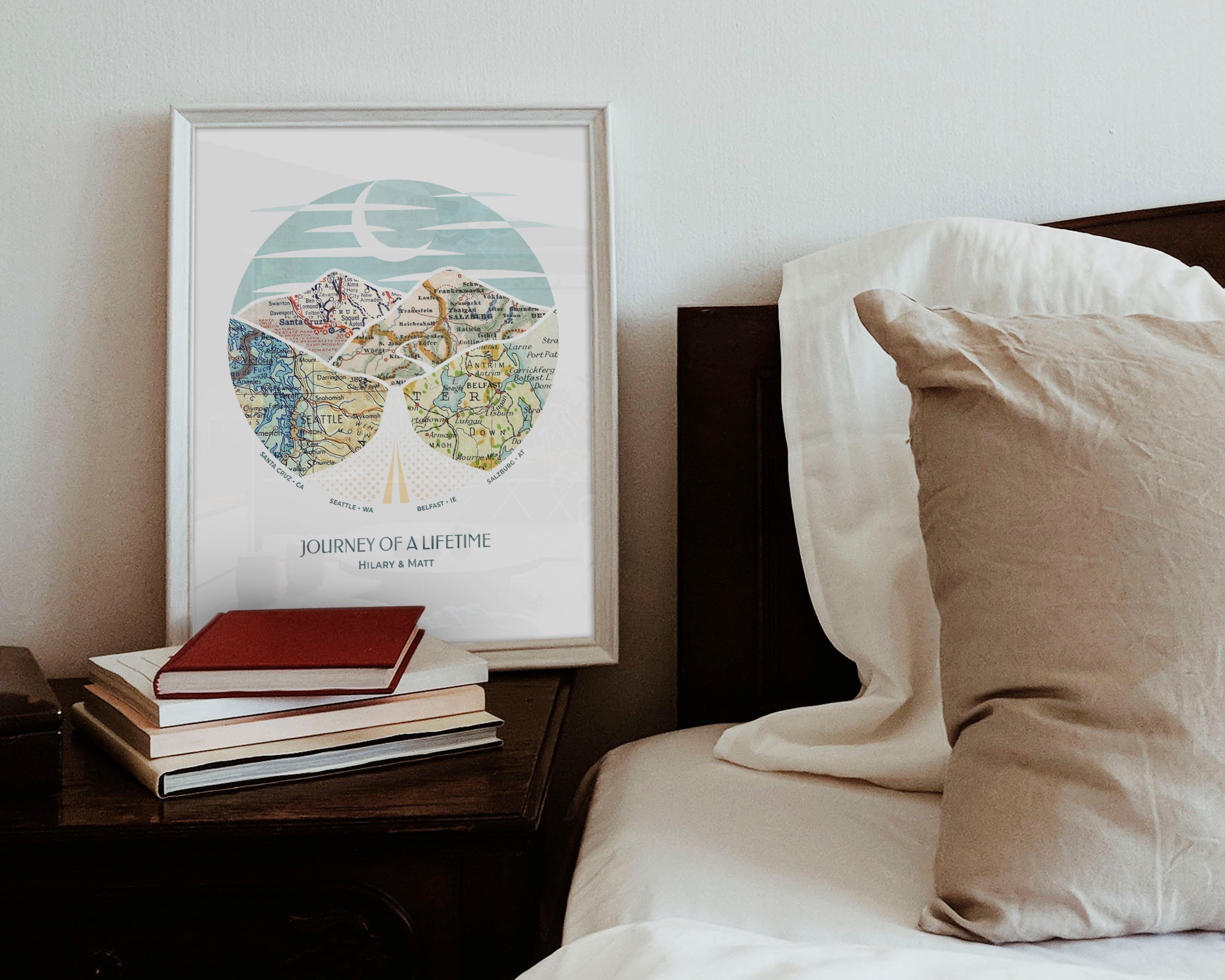 wanderlust roadtrip map print four maps white frame. Relief of hills and highway into the horizon, with inset maps. On bedside counter.